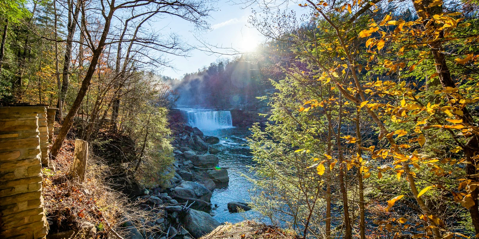 Falls and wooded river gorge in daylight.