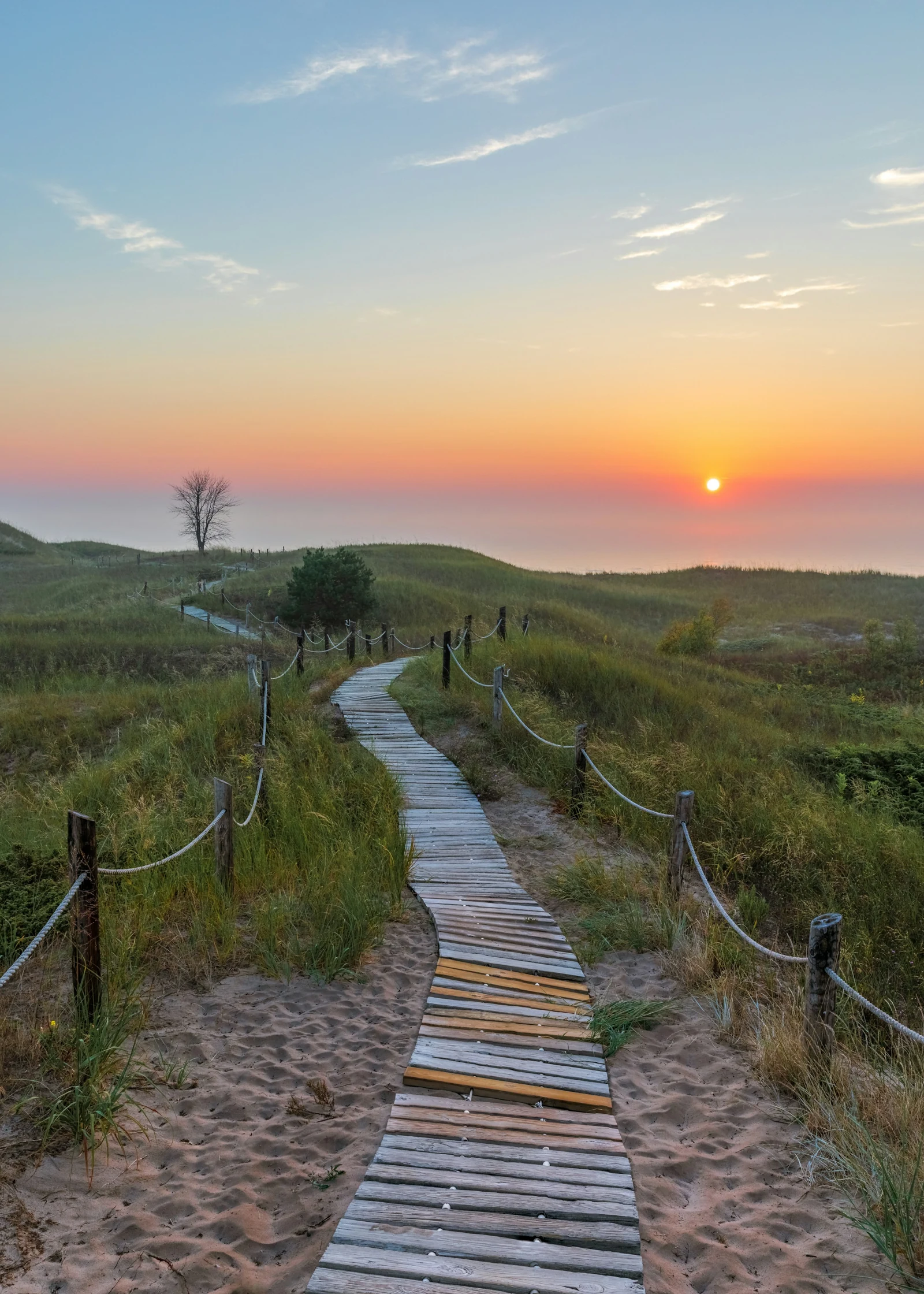 Dune boardwalk toward Lake Michigan in low light.